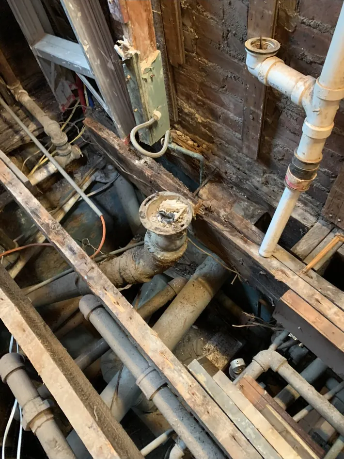 Bathroom floor opened to expose plumbing during a remodel