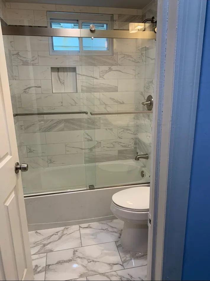 Completed bathroom remodel with tiled tub surround and vanity